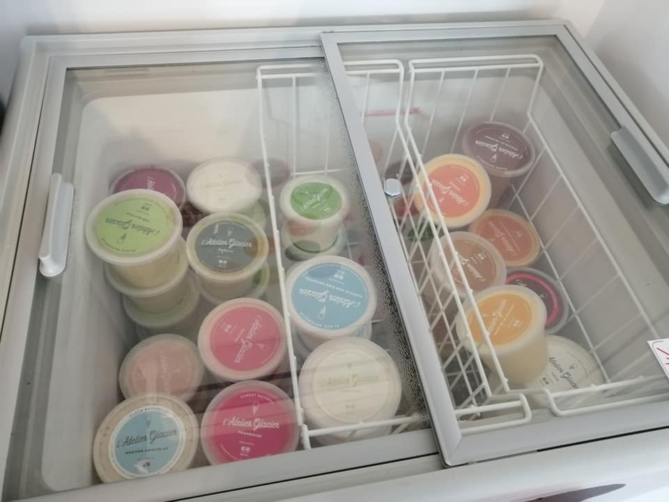 Pots de glaces artisanales dans un congélateur vitré.