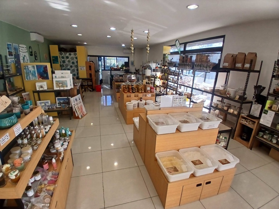 Intérieur de la boutique : îlots de bacs de vrac, distributeurs de graines et étagères de produits.