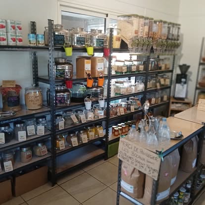 Étagères de l'épicerie : bocaux de vrac, sachets, conserves et distributeurs.